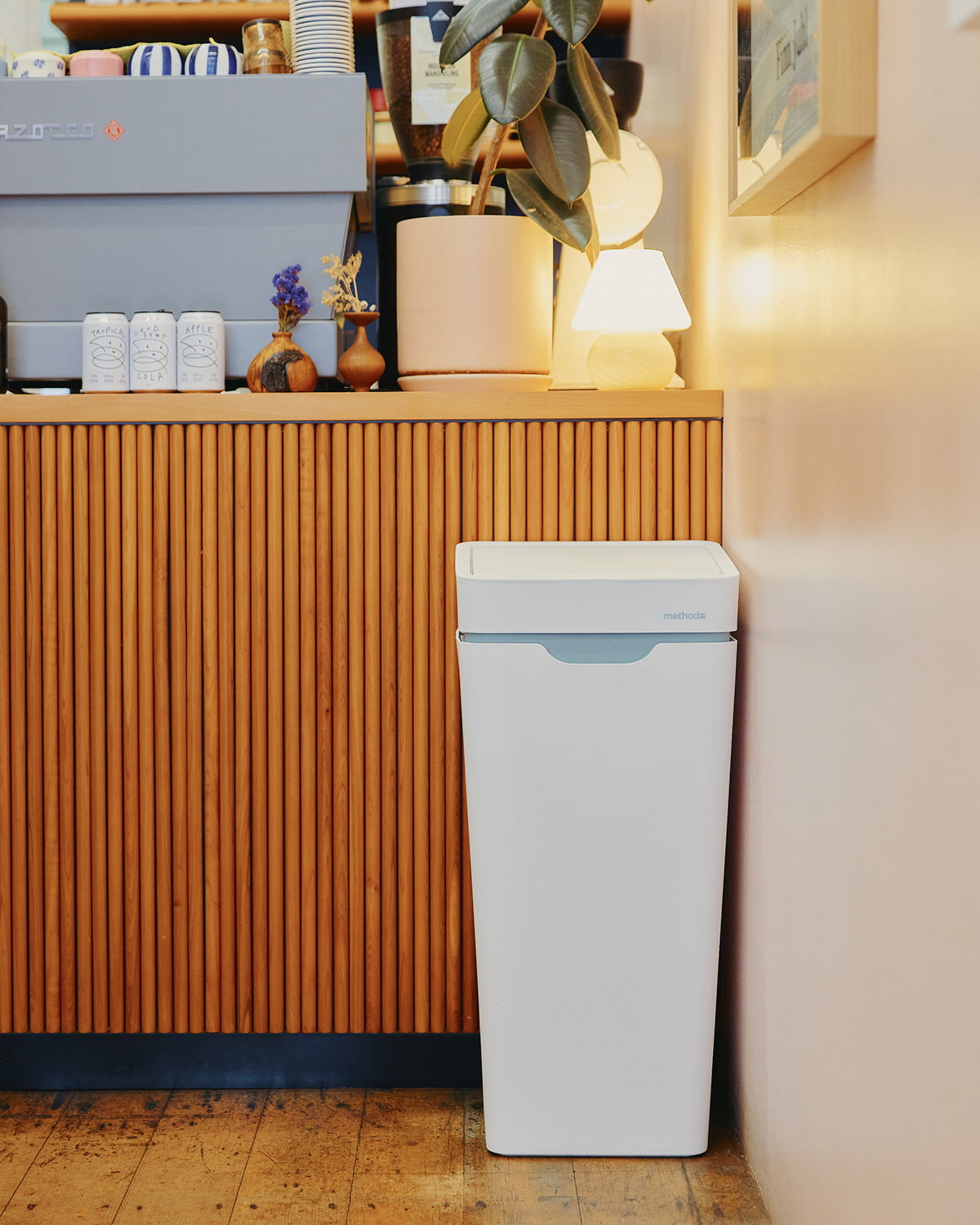 A white Mono at the end of a fluted timber café counter, below an espresso machine and a lamp