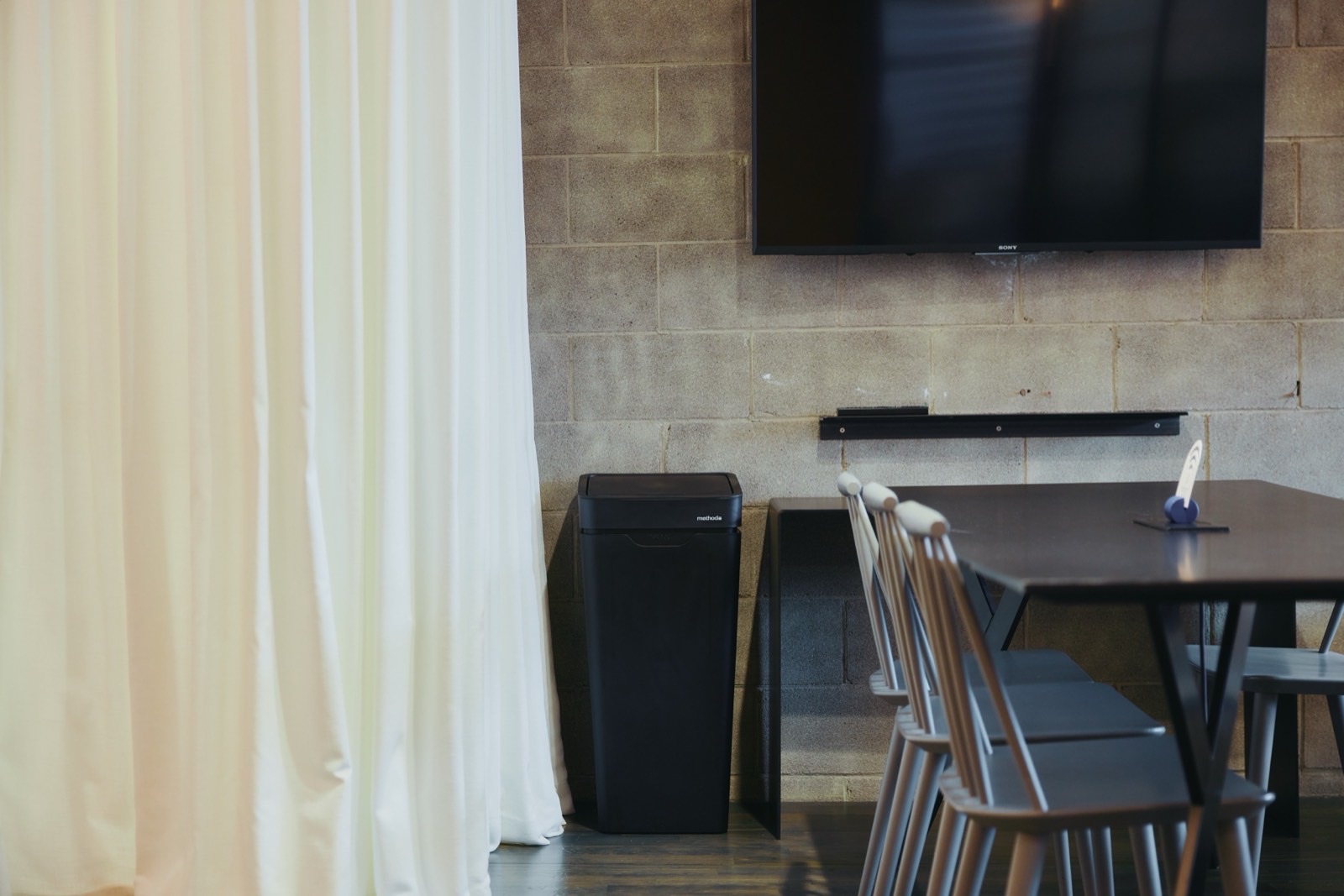 A black Mono against a stone wall beside a meeting table and chairs
